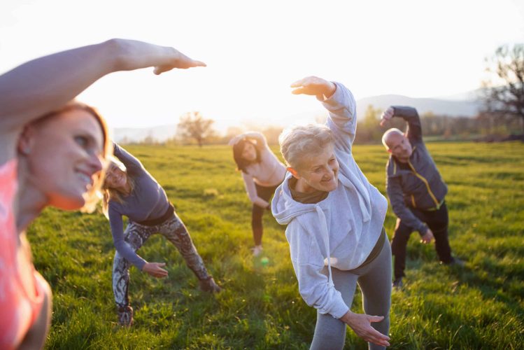 Group of seniors with sport instructor doing exercise outdoors in nature at sunset, active lifestyle. A group of seniors with sport instructor doing exercise outdoors in nature at sunset, active lifestyle.